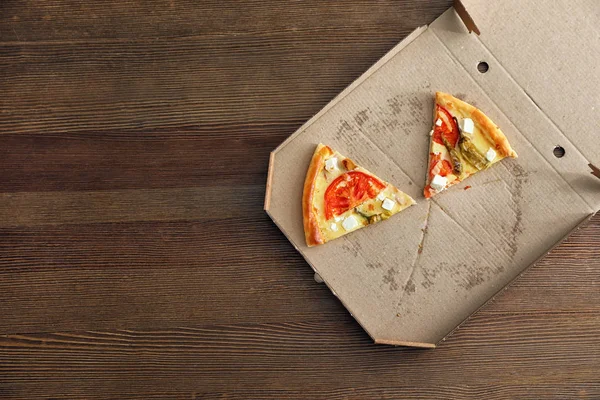 Caja de cartón con sabrosas rebanadas de pizza sobre fondo de madera, vista superior. Espacio para texto — Foto de Stock