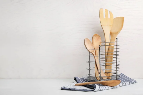 Suporte com utensílios de cozinha de madeira e guardanapo na mesa. Espaço para texto — Fotografia de Stock