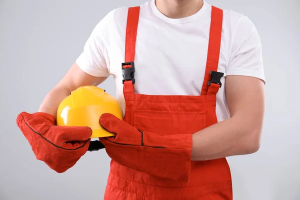 Mannelijke industriële werknemer in uniform op lichte achtergrond, close-up. Veiligheidsuitrusting — Stockfoto