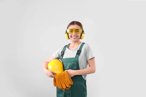 Industriële werkneemster in uniform op lichte achtergrond. Veiligheidsuitrusting — Stockfoto