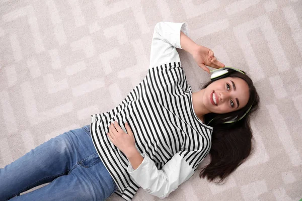 Fiatal nő fejhallgató élvez zene padlón, felülnézet — Stock Fotó