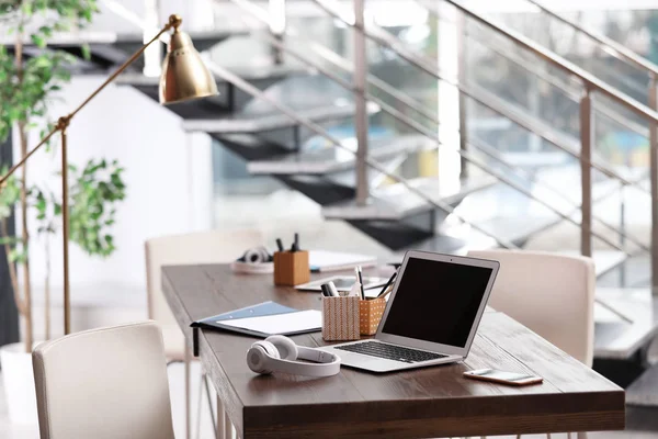 Local de trabalho com laptop e fones de ouvido no escritório moderno — Fotografia de Stock