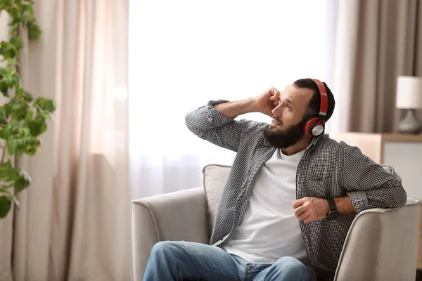 Ώριμος άνδρας με τα ακουστικά που αναπαύεται στην πολυθρόνα στο σπίτι — Φωτογραφία Αρχείου