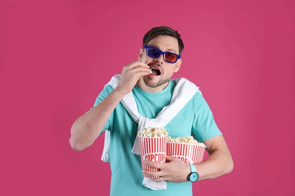 Man with 3D glasses eating tasty popcorn on color background — Stock Photo, Image
