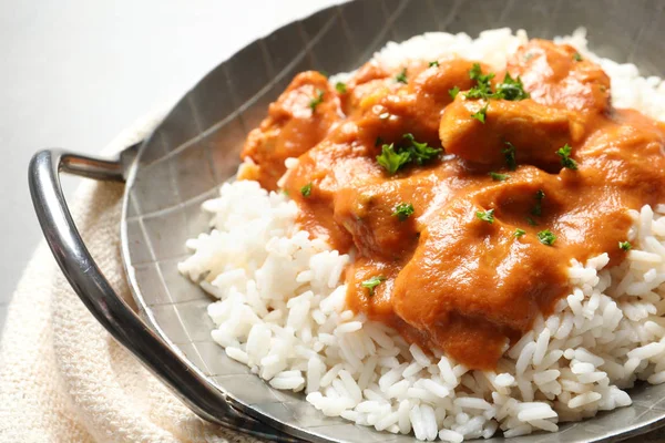 Delicious butter chicken with rice in dish and napkin on table