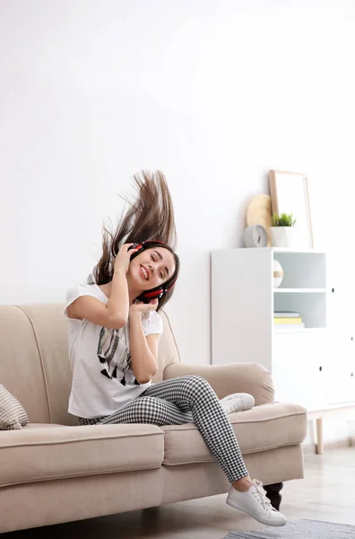 Junge Frau mit Kopfhörer genießt Musik auf dem heimischen Sofa — Stockfoto