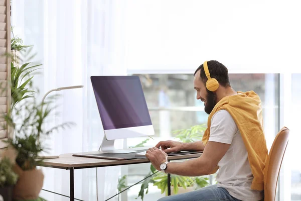 Hombre maduro con auriculares y computadora en la oficina en casa —  Fotos de Stock