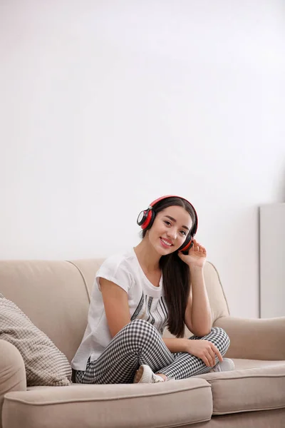 Jeune femme dans un casque profitant de la musique sur le canapé à la maison — Photo