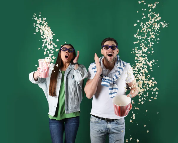 Pareja emocional con gafas 3D lanzando palomitas de maíz sobre fondo de color — Foto de Stock