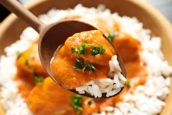 Spoon with tasty butter chicken over bowl of meal, closeup — Stock Photo, Image
