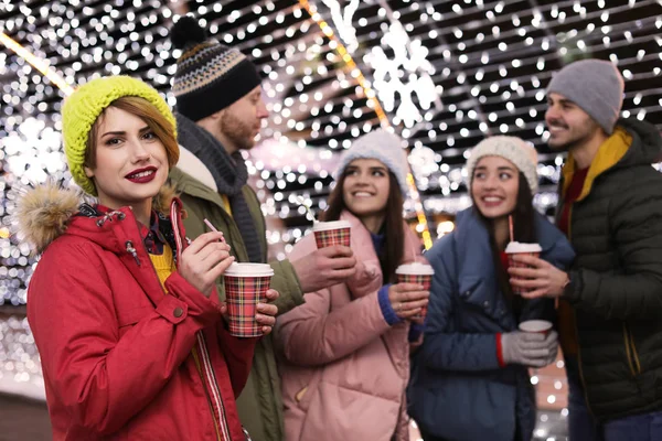 Happy friends with cups of mulled wine at winter fair — Stock Photo, Image