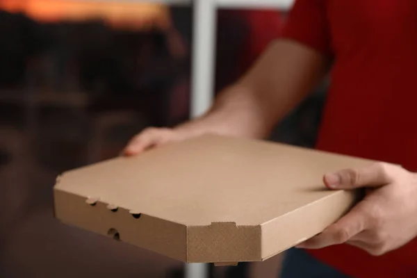Кур'єр з коробкою для піци на розмитому фоні, крупним планом. Простір для тексту — стокове фото
