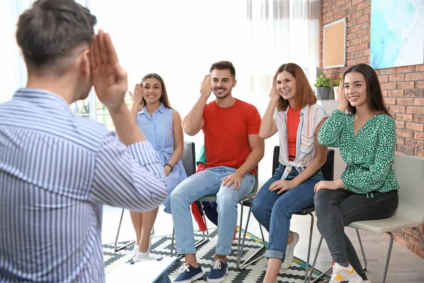 Grupo de jóvenes que aprenden el lenguaje de señas con el profesor en interiores — Foto de Stock