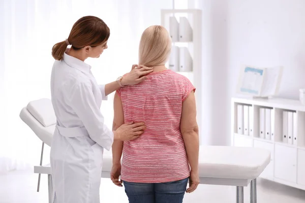 Хиропрактик осматривает пациента с болью в спине в клинике — стоковое фото