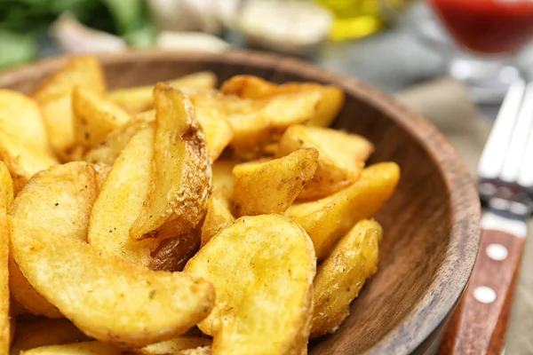 Ciotola con gustosi cunei di patate al forno sul tavolo, primo piano — Foto Stock