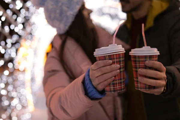 Young couple with cups of mulled wine at winter fair, closeup — Stock Photo, Image