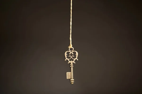 青铜复古华丽的钥匙挂在黑暗的背景下的线程 — 图库照片