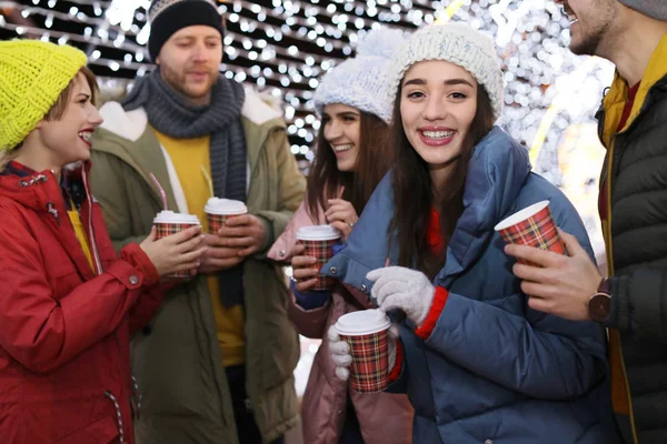 Щасливі друзі з чашками глінтвейну на зимовому ярмарку — стокове фото