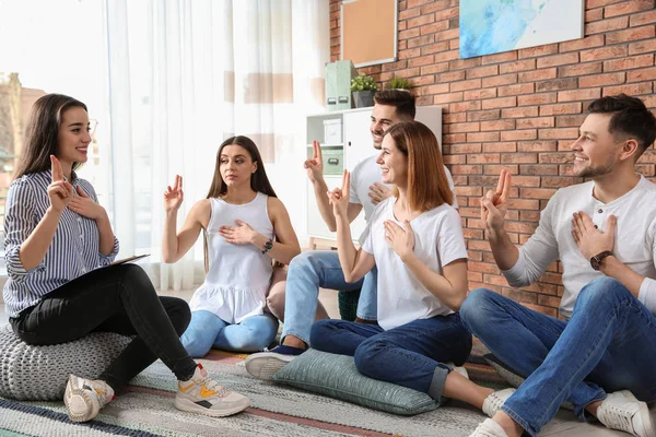 Grupo de jóvenes que aprenden el lenguaje de señas con el profesor en interiores — Foto de Stock