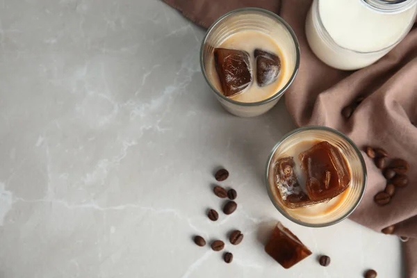 Glasses of milk with coffee ice cubes on grey table, top view. Space for text — Stock Photo, Image