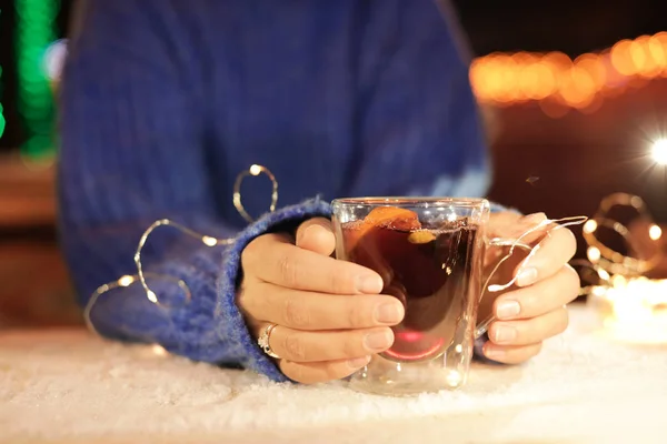 Nő, csésze forralt bor és havas asztalnál, Vértes garland — Stock Fotó