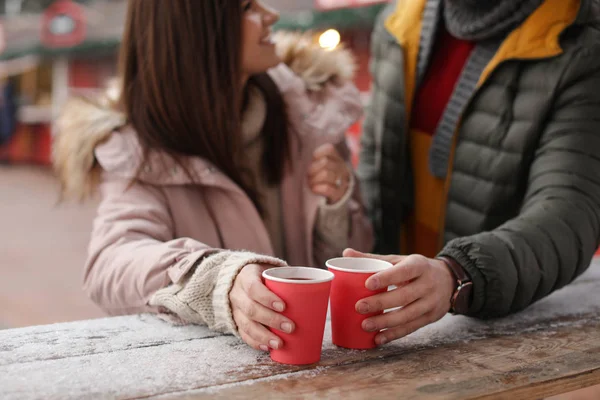 Young couple with cups of mulled wine at winter fair, closeup — Stock Photo, Image
