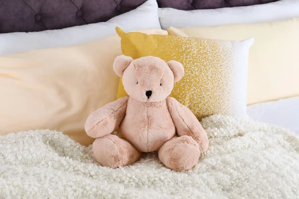 Lindo oso de peluche sentado en la cama en interiores — Foto de Stock