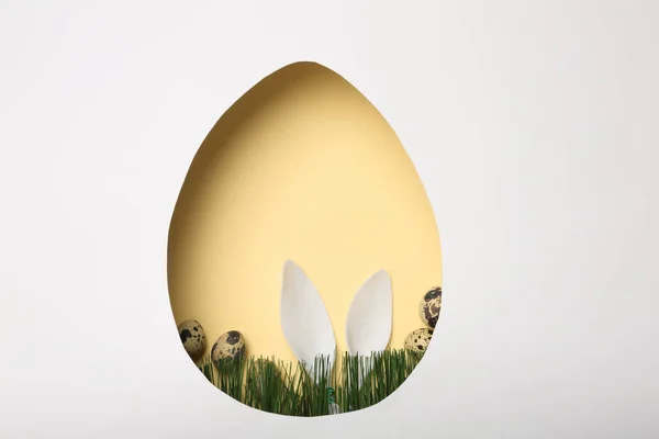 Vista della composizione con orecchie di coniglio pasquali su sfondo a colori attraverso foro a forma di uovo, vista dall'alto. Spazio per testo — Foto Stock