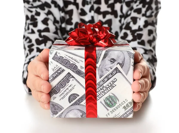 Mujer sosteniendo caja de regalo envuelta en papel decorativo con patrón de dólar sobre fondo blanco, primer plano — Foto de Stock