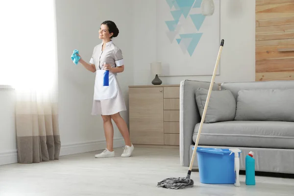 Young maid with rag and detergent in hotel room — Stock Photo, Image