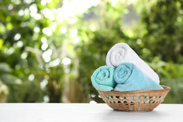 Basket with soft bath towels on table against blurred background. Space for text — Stock Photo, Image
