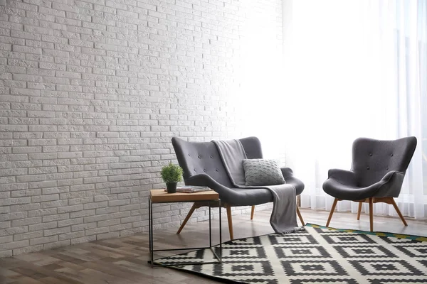 Sofá elegante y sillón cerca de la pared de ladrillo en el interior de la sala de estar moderna. Espacio para texto —  Fotos de Stock