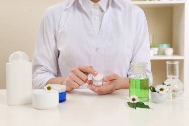 Kadın dermatolog cilt bakım ürünü masada, closeup test