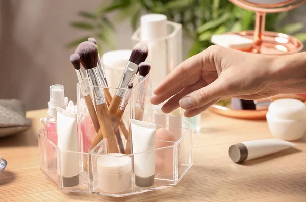 Woman taking cosmetic products from holder on dressing table, closeup — Stock Photo, Image