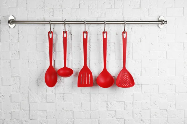 Bastidor con utensilios de cocina limpios en la pared blanca — Foto de Stock