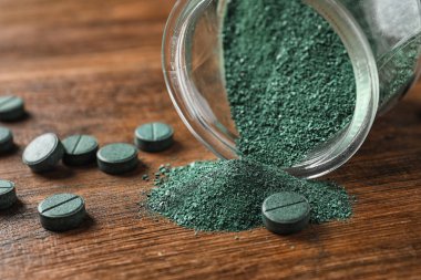 Spirulina tozu ve ahşap masa, closeup haplarla kavanoz