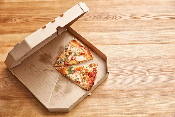 Caja de cartón con piezas de pizza sobre mesa de madera. Espacio para texto — Foto de Stock