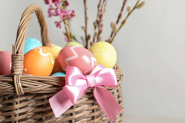 柳条篮子与彩绘复活节彩蛋和花在颜色背景, 特写镜头 — 图库照片