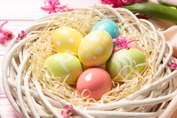柳条巢与五颜六色的彩绘复活节彩蛋在桌子上, 特写镜头 — 图库照片