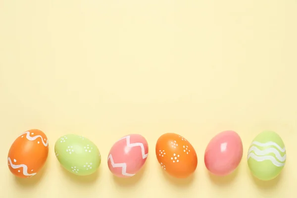 Плоская композиция окрашенных пасхальных яиц на цветном фоне, пространство для текста — стоковое фото