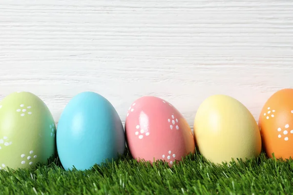 Renkli boyalı Paskalya yumurtaları yeşil çim ahşap arka plan, metin için yer — Stok fotoğraf