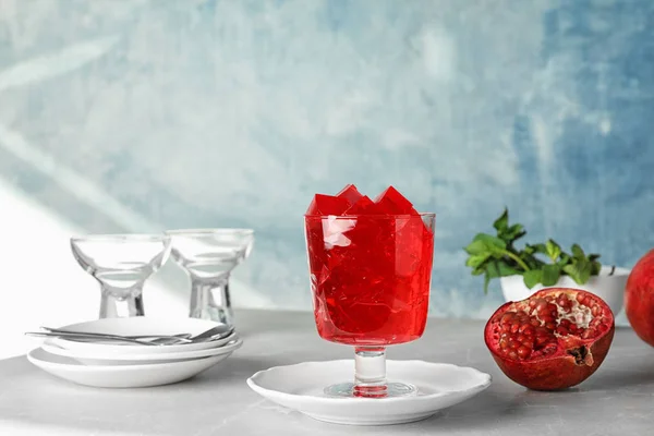 Sammansättning med glas granatäpple gelé på bordet mot färgbakgrund. Utrymme för text — Stockfoto