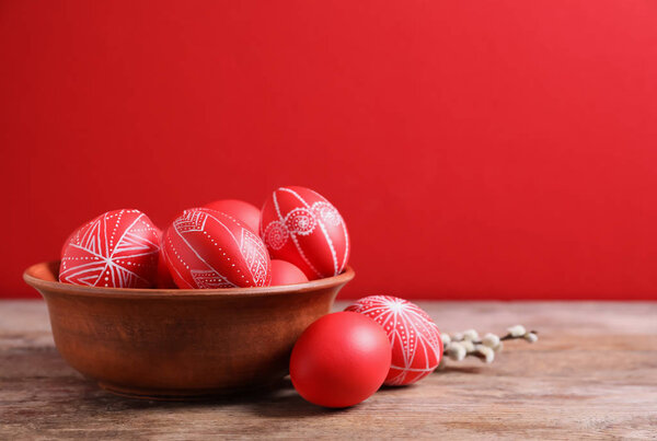 Cuenco de madera con huevos de Pascua pintados de rojo en la mesa contra el fondo de color, espacio para el texto — Foto de Stock