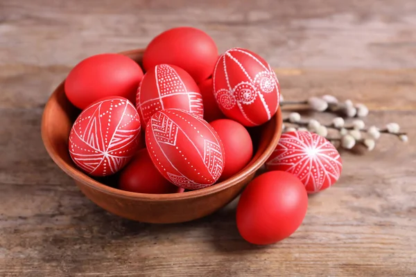 Ciotola di legno con uova di Pasqua dipinte di rosso sul tavolo — Foto Stock