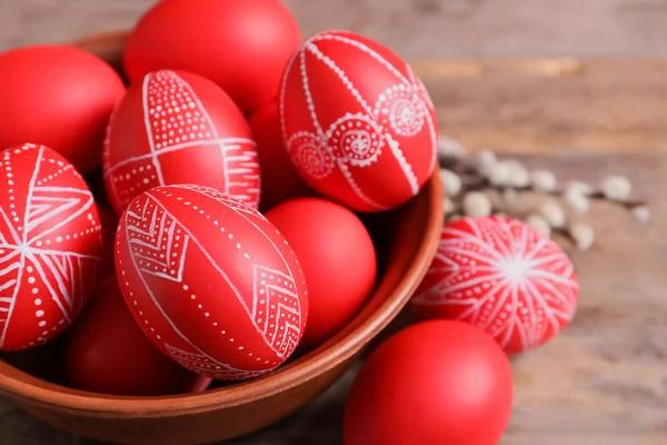 Ciotola di legno con uova di Pasqua dipinte di rosso sul tavolo, primo piano — Foto Stock