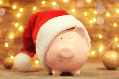Bulanık ışıklar karşı masada Noel Baba şapkası ile şirin kumbara