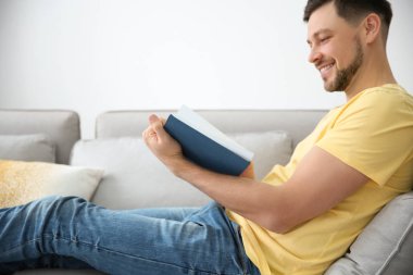 yakışıklı adam evde kanepede kitap okuma