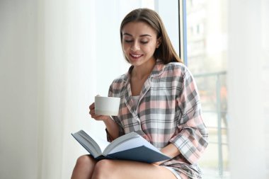 Fincan kahve okuma kitabı evde pencere yanında olan kadın