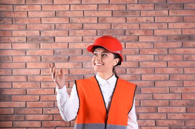 Tuğla duvar arka plan üzerinde üniformalı kadın endüstri mühendisi. Güvenlik ekipmanları