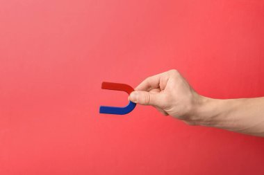 Man holding magnet on color background, closeup. Space for text clipart